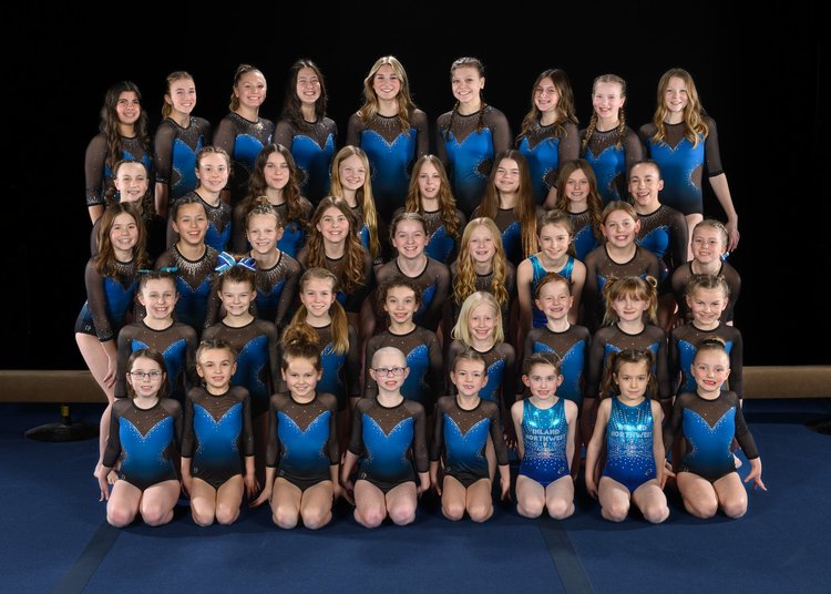 Large group photo of a gymnastics team in matching blue leotards
