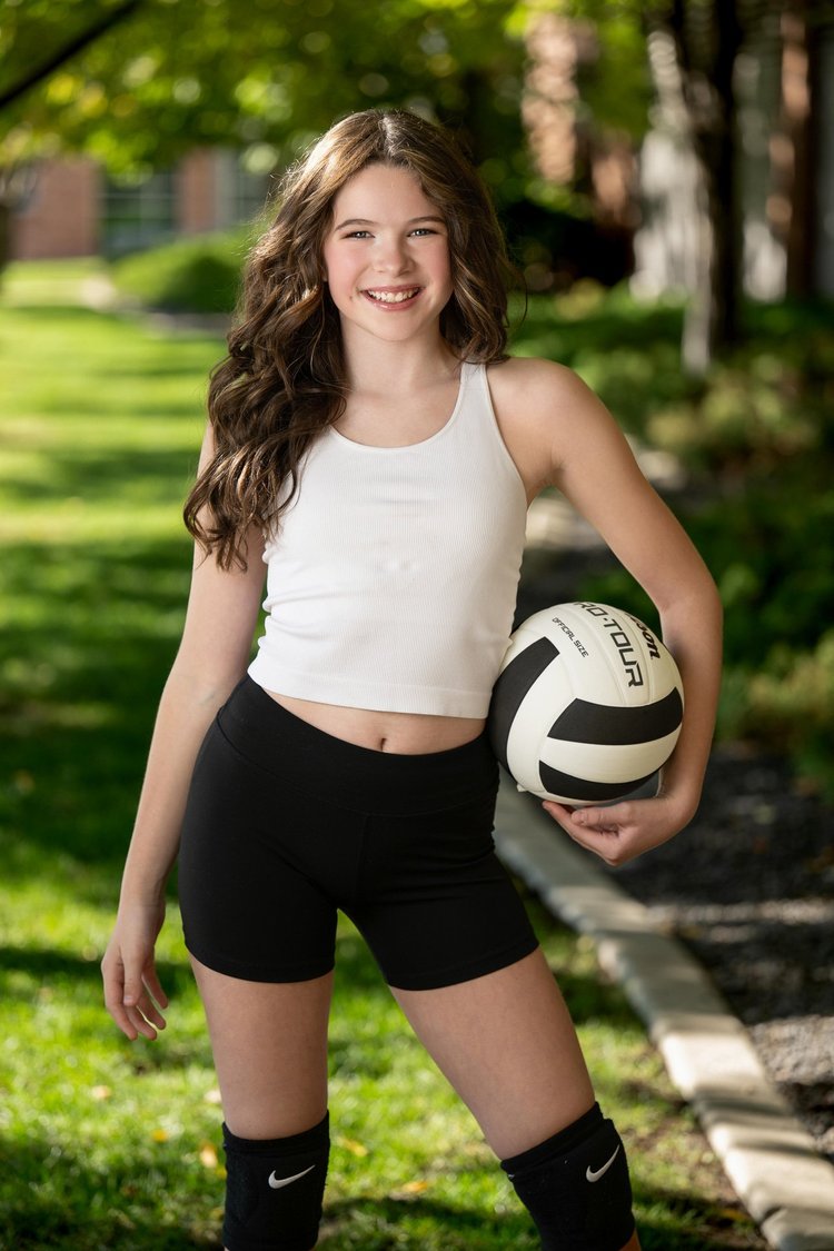 Senior portrait of a volleyball player holding a ball outdoors
