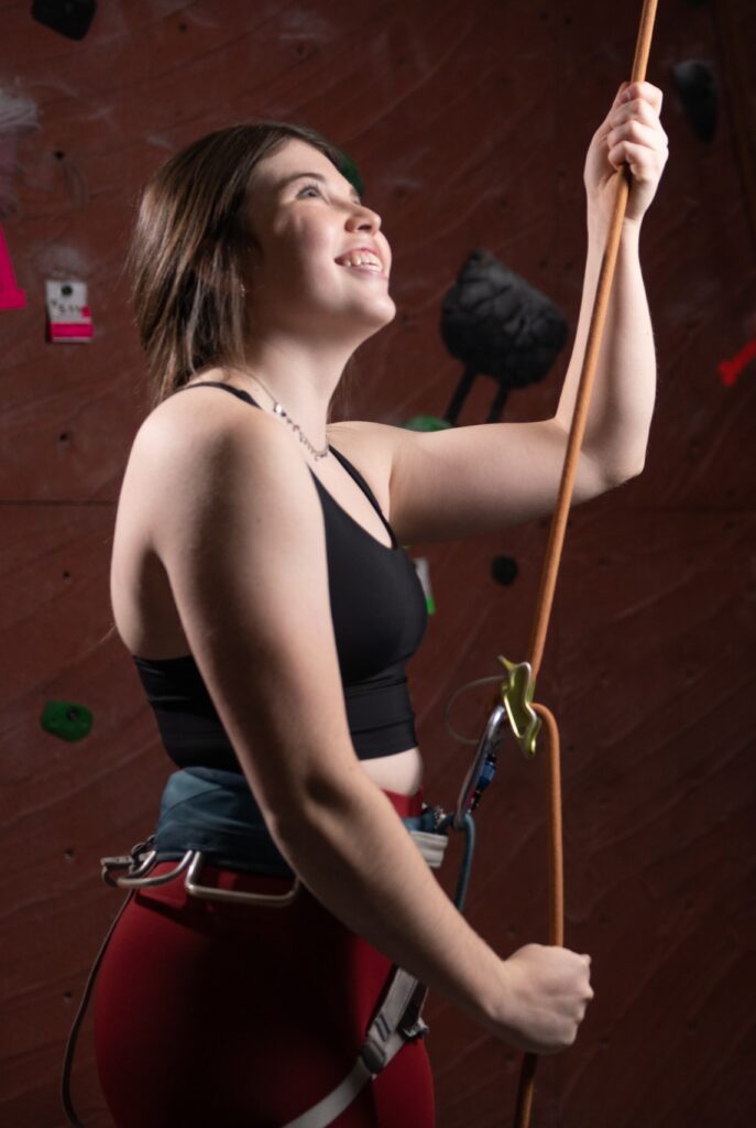 A girl belaying a climber at the gym