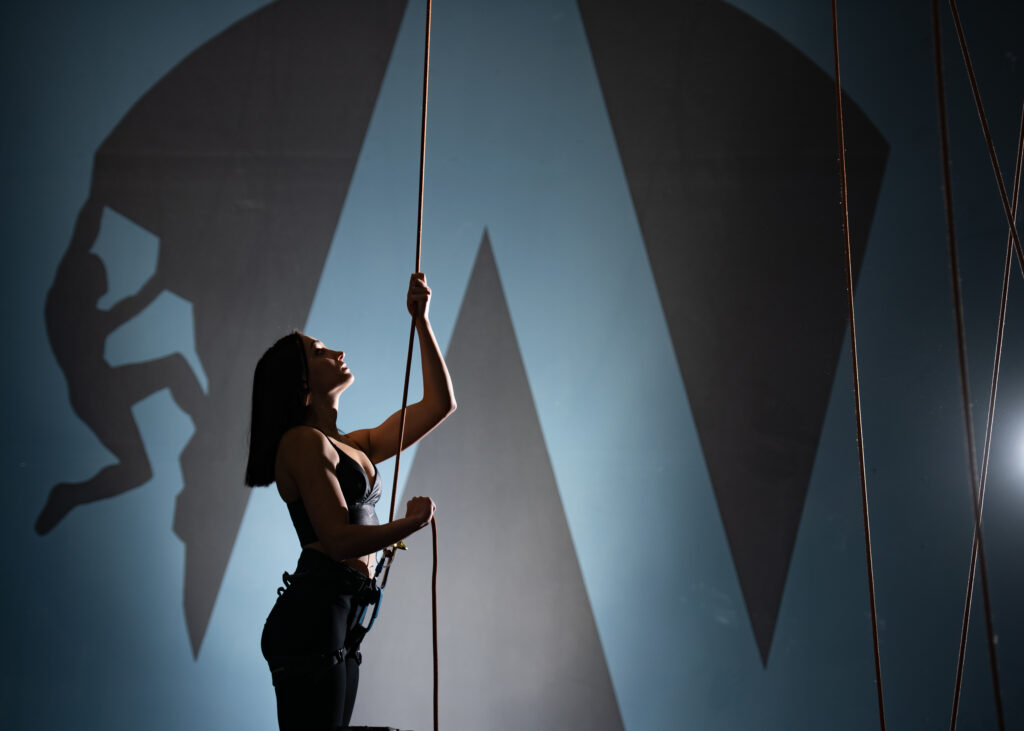 A girl belaying a climber in a climbing gym